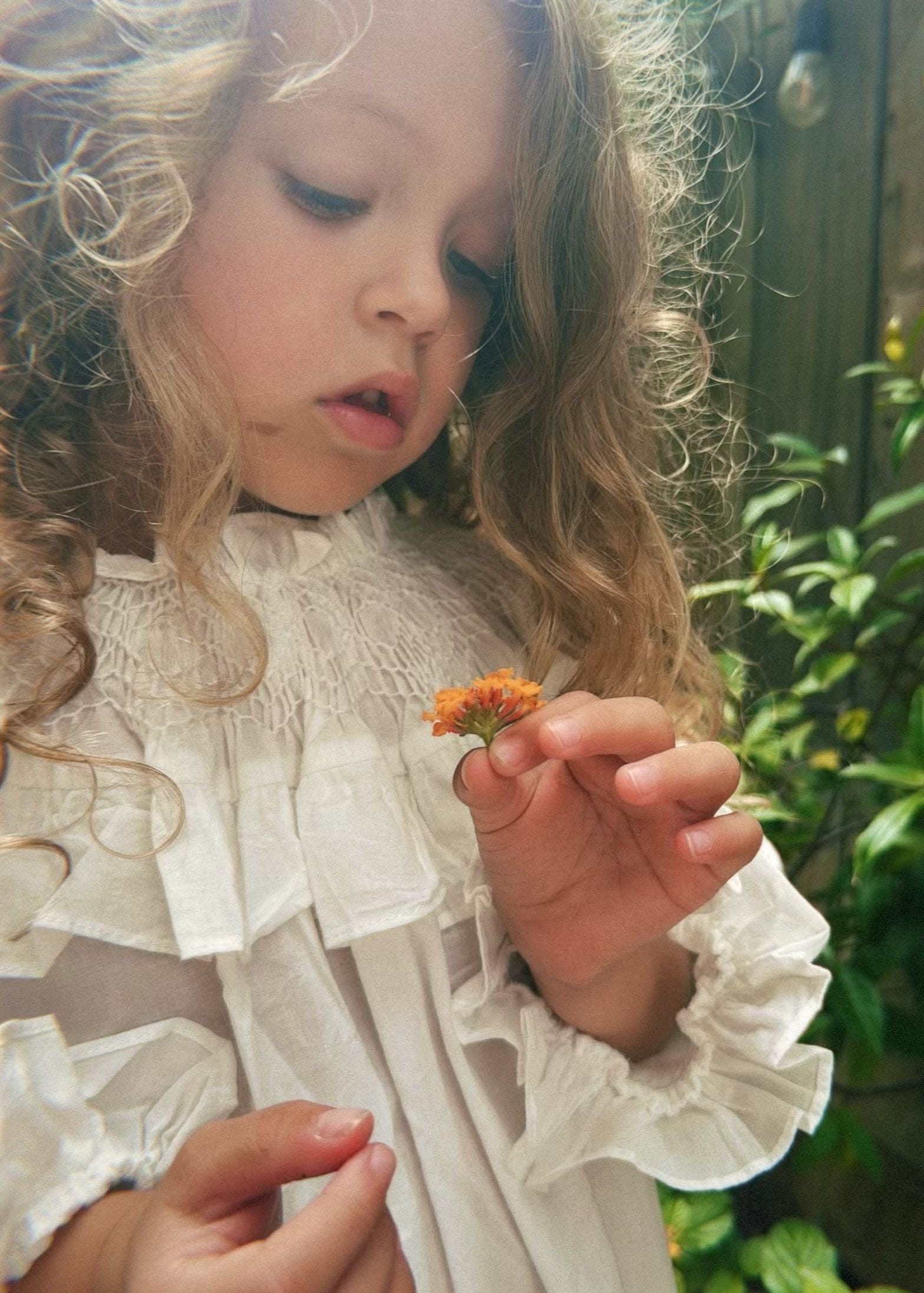 mi regalia 100% cotton loungewear dress seen on a little girl holding an orange flower.